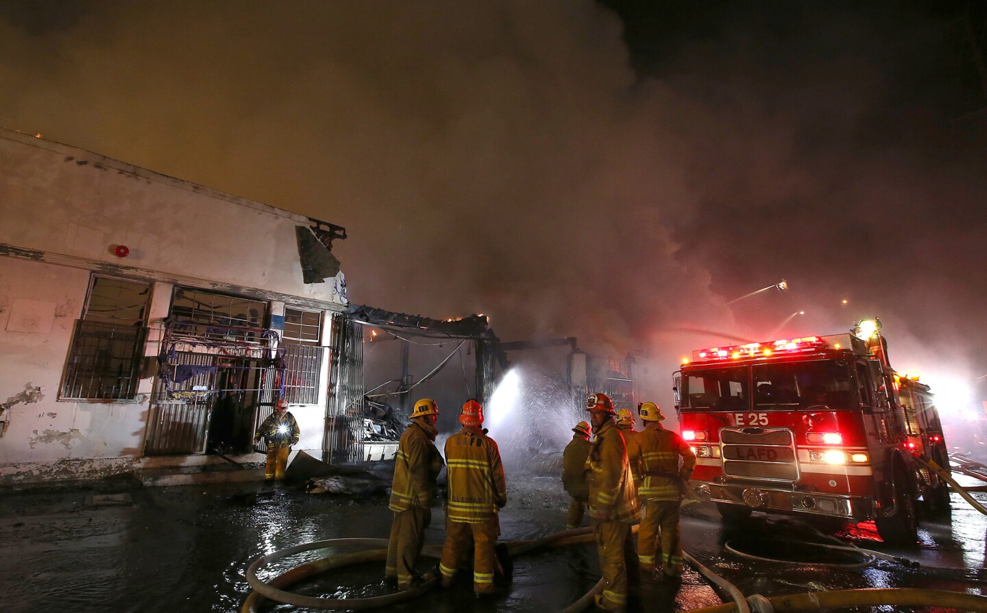 Firefighters confer during their battle against the blaze at a a commercial building near the intersection of Soto Street and Olympic Bouevard in Boyle Heights.
