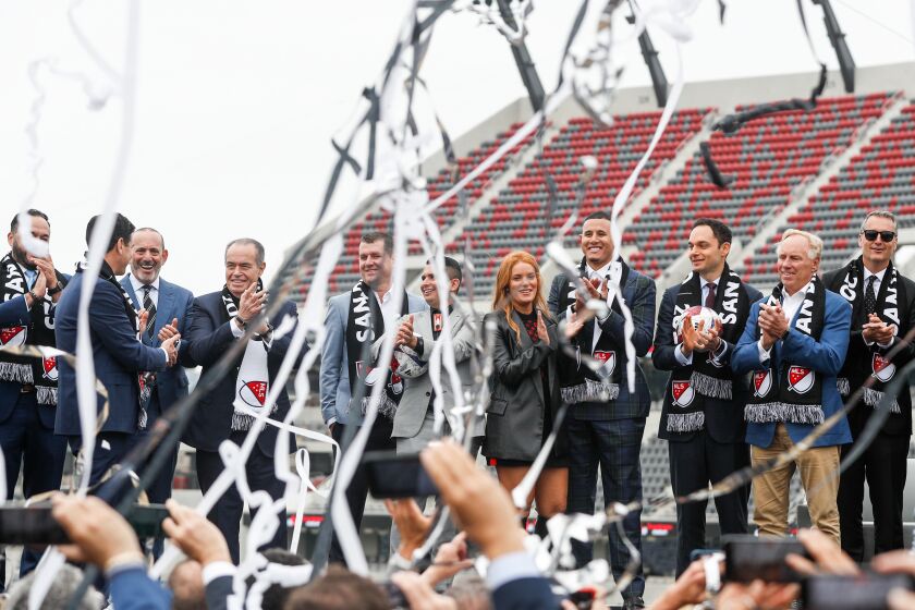 San Diego, CA - May 18: Various owners and affiliates smile and applaud as streamers fall near the stage during an event to unveil San Diego as the home of Major League Soccer's 30th franchise at Snapdragon Stadium on Thursday, May 18, 2023 in San Diego, CA. (Meg McLaughlin / The San Diego Union-Tribune)