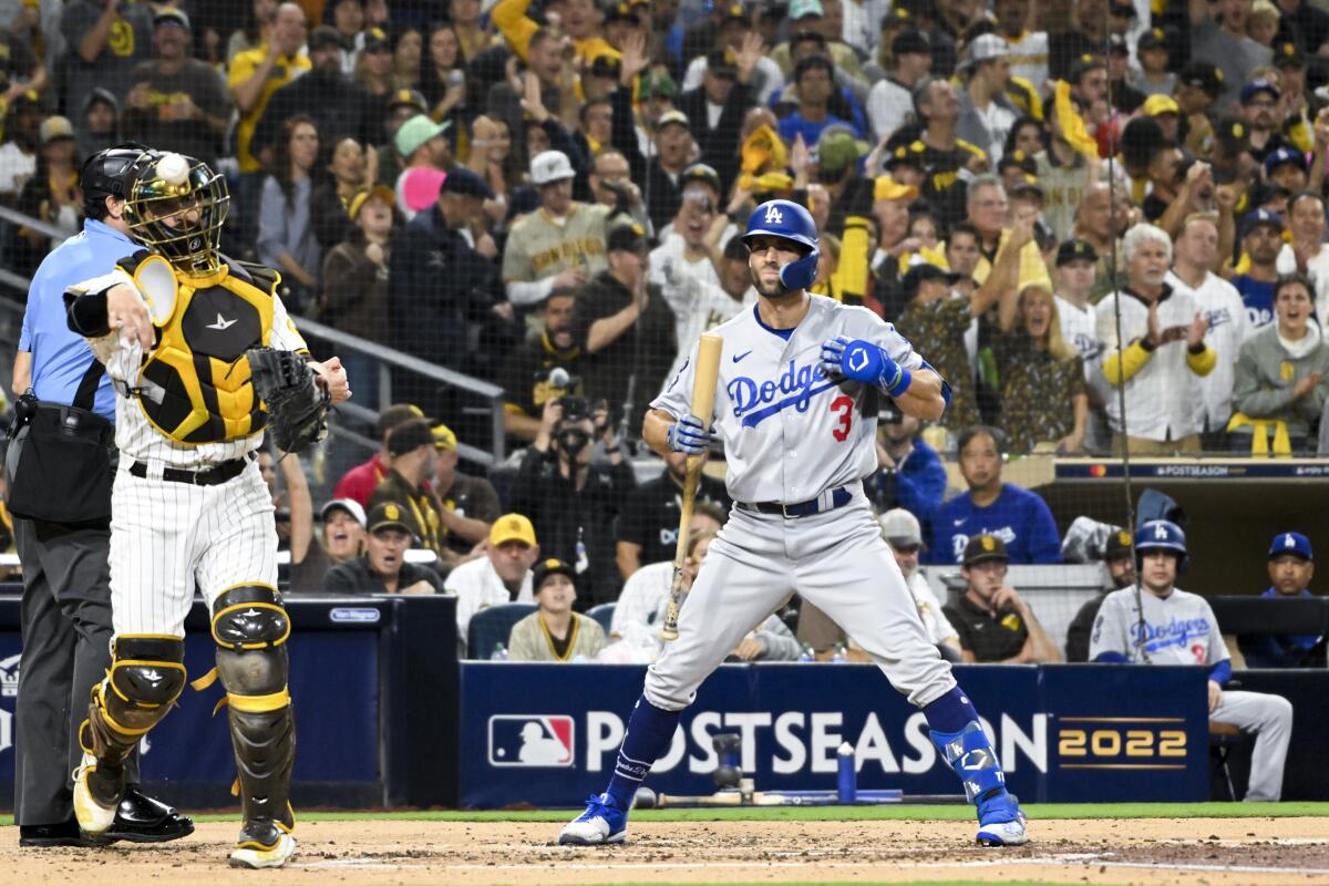 Dodgers' Chris Taylor holds bat and touches shirt after striking out.