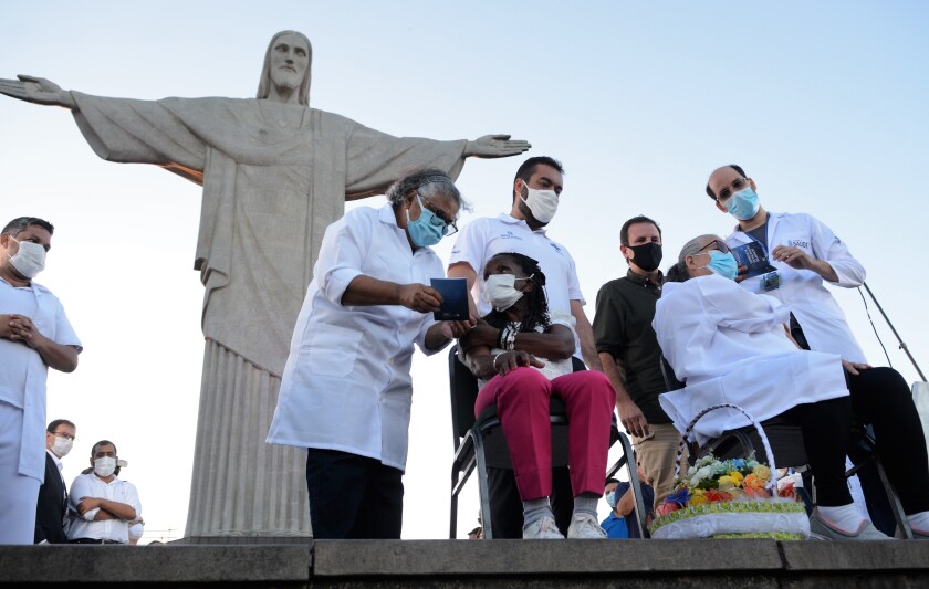 Two residents of Rio de Janeiro are vaccinated at Christ the Redeemer.
