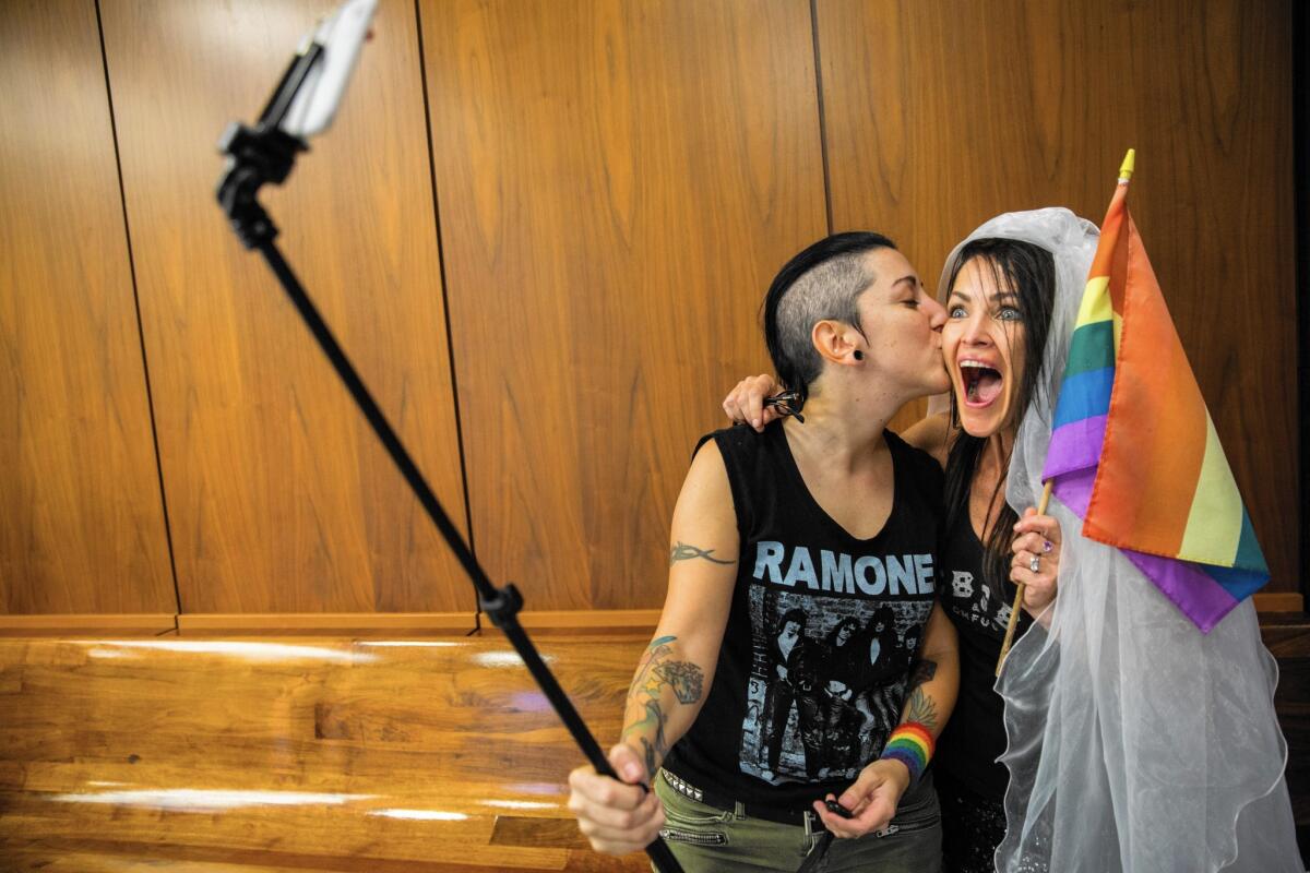 Natalie Novoa, left, left, and Eddie Daniels take a selfie while waiting to be married at the L.A. County registrar’s Beverly Hills office on Friday.