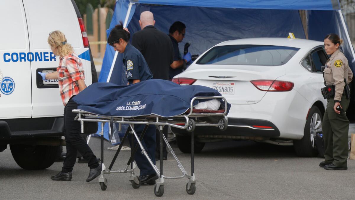 L.A. County Coroner officials remove the body of a man found in a parked car in August on West 108th Street in the Willowbrook area.