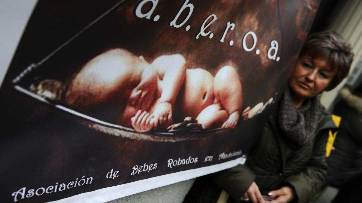 A woman poses next to a poster of the Andalusian Stolen Babies Assn. during a demonstration against baby trafficking in Madrid.