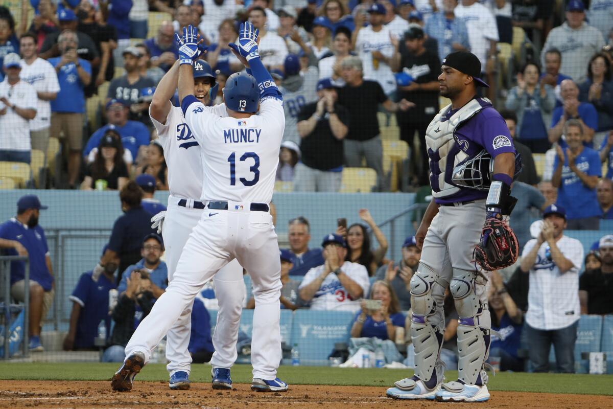 Colorado Rockies catcher Elias Diaz looks on as Dodgers' Will Smith and Max Muncy celebrate.
