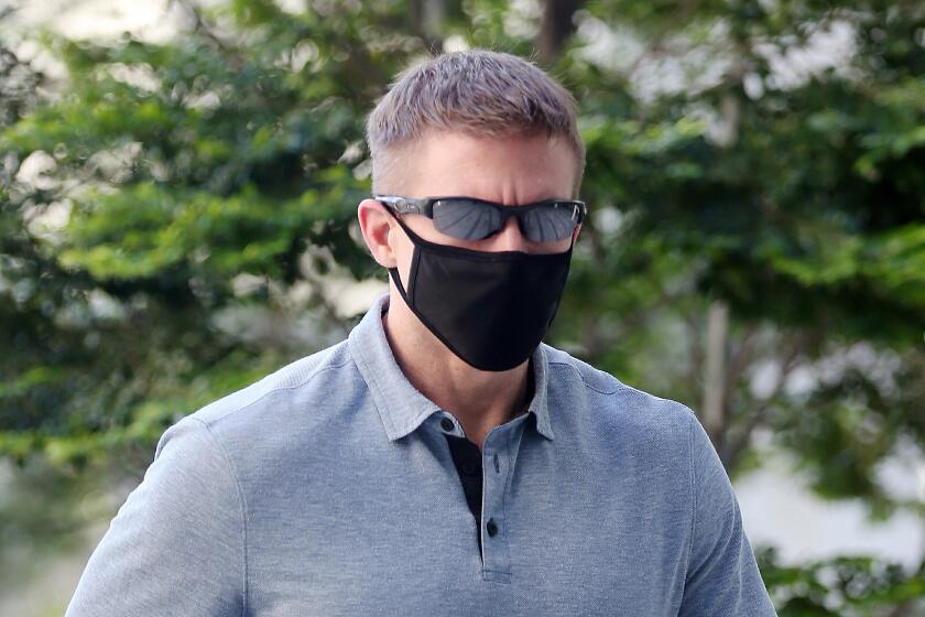 In this May 13, 2020, photo, Brian Dugan Yeargan, wearing a face mask and sunglasses, walks outside the Singapore State Court in Singapore. The 44-year-old American pilot has been jailed for four weeks for breaching a quarantine order in Singapore. Local media reported that Brian Dugan Yeargan was sentenced by a court Wednesday, May 13 for leaving his hotel room for three hours to buy masks and a thermometer. (The Strait Times via AP)