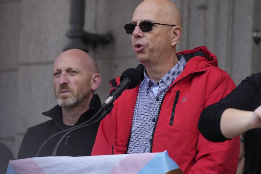 Co-owners of Club Q, Matthew Haynes, front, and Nic Grzecka, address the crowd after a 25-foot historic pride flag was displayed on the exterior of City Hall to mark the weekend mass shooting at the gay nightclub Wednesday, Nov. 23, 2022, in Colorado Springs, Colo. The flag, known as Section 93 of the Sea to Sea Flag, is on loan for two weeks to Colorado Springs from the Sacred Cloth Project. (AP Photo/David Zalubowski)