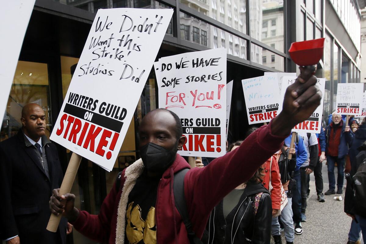 Demonstrators carry picket signs during a screenwriter's strike in New York City.