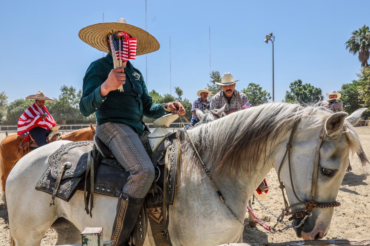 Un hombre a caballo que lleva una pequeña bandera estadounidense.