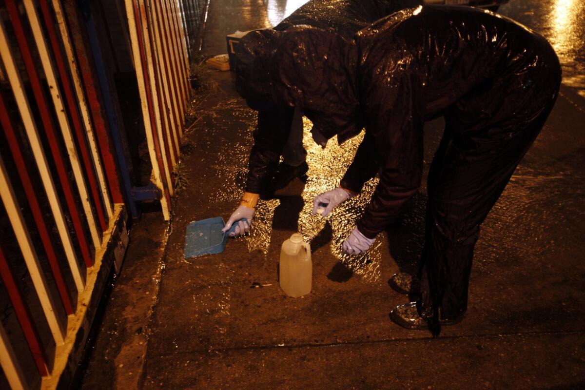 Michael Quill, left, and Lara Meeker at work. Whenever a storm hits and gutters start to gurgle, L.A. Waterkeeper staffers and volunteers pull on their parkas, headlamps and rubber boots. They make unannounced visits to lonely streets on the county's industrial fringes.