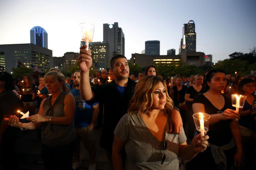 Dallas Police Officer Victor Guzman, who was on the sniper shooting scene, holds a candle with his wife Ciprina as family and friends of fallen police officers take part in a candlelight vigil at City Hall in Dallas.