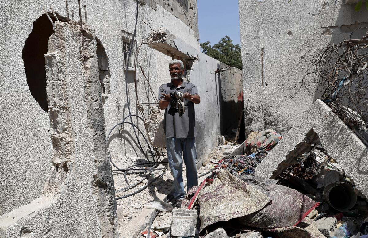Nasser Abu Fares, who lost three daughters and a grandson when an Israeli artillery bombardment hit his family house during the 11-day war between Israel and Gaza's Hamas rulers in May, shows the shoes of one of his daughters amid the rubble of his house, at the Bedouin village of Umm Al-Nasr, outside the town of Beit Lahia, northern Gaza Strip, Wednesday, Aug. 4, 2021. After initially finding no grounds for disciplinary action, the Israeli military says it is investigating the artillery bombardment that killed six Palestinians, including an infant, in the Gaza Strip last May. (AP Photo/Adel Hana)