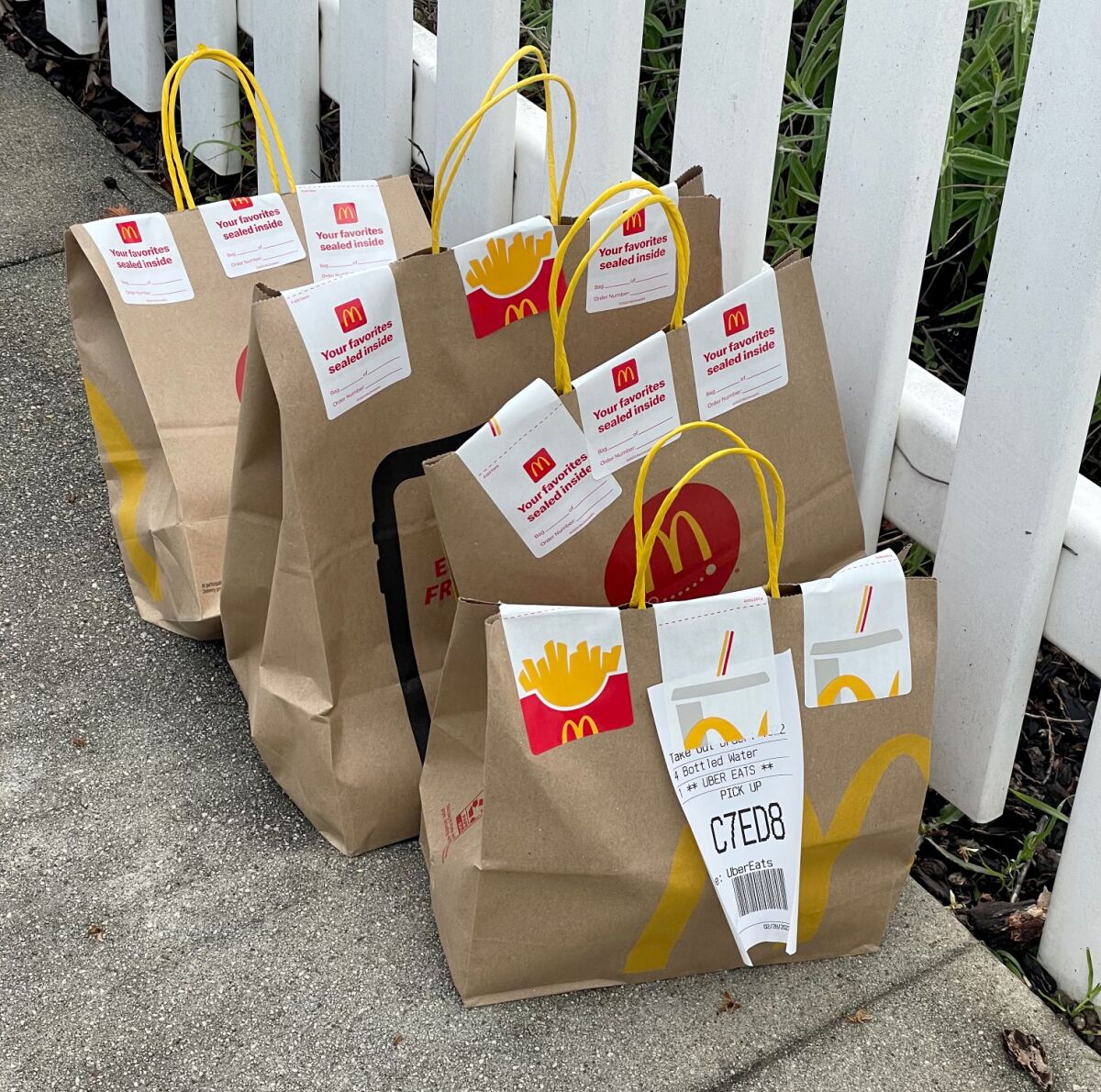 Four McDonald's bags delivered by Uber Eats sit in front of a home in Highland Park.