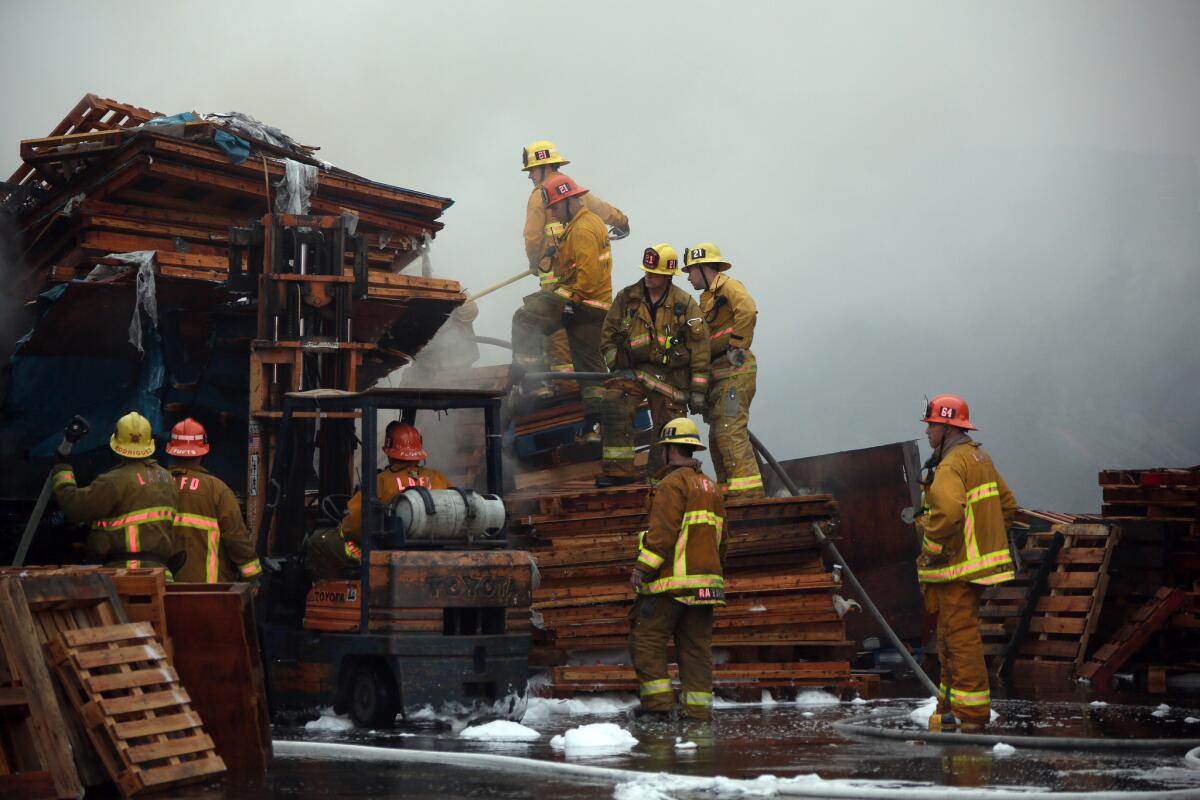 Los Angeles city firefighters put out hot spots after a fire at a pallet yard in South Los Angeles early Friday morning.