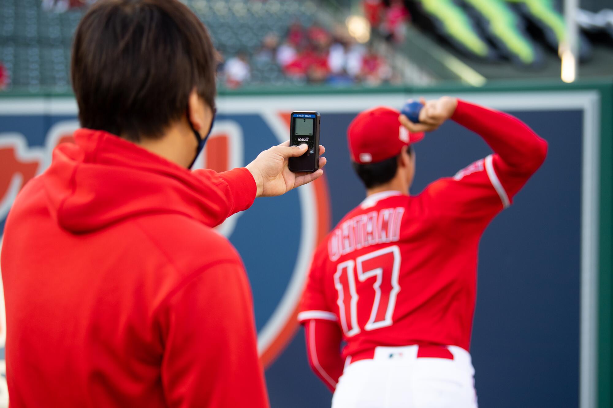 Shohei Ohtani's translator, Ippei Mizuhara, measures Ohtani's throwing speed using a pocket radar.