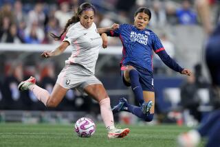 Angel City FC forward Sydney Leroux prepares to clear the ball against OL Reign defender.