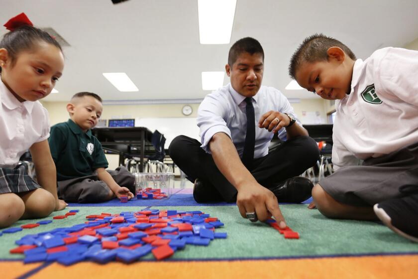 LOS ANGELES, CA - AUGUST 13, 2018: Ruben Alonzo, Executive Director of Excelencia Charter Academy gets down on the floor with Kindergarten students Darlene Morales, Azariah Terrazas and Adrian Vargas, left to right, in one of the classrooms located on the grounds of Sunrise Elementary located at 2821 E 7th St near downtown Los Angeles where the two schools share a campus August 13, 2018. Tensions are common and can run deep when traditional schools must share their campuses with charter schools. Teachers and parents from Sunrise Elementary have been protesting the arrival of the new Excelencia Charter Academy. (Al Seib / Los Angeles Times)