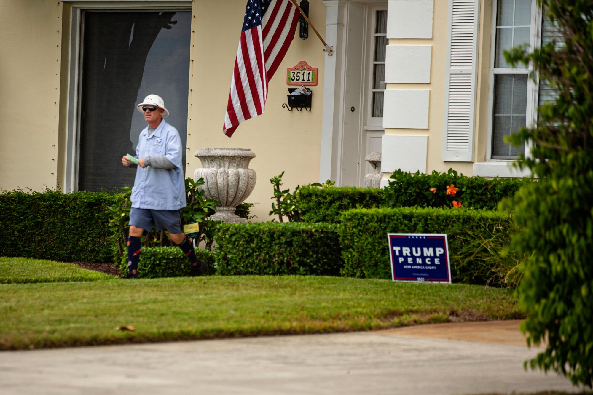 A postman leaves a West Palm Beach home with a yard sign for President Trump in the lawn.