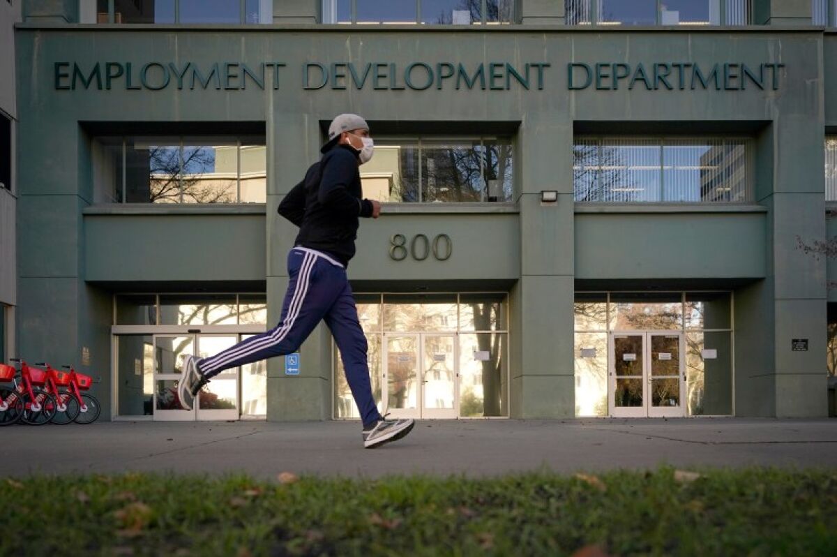 A person jogs past a building with the words "Employment Development Department" on its front.