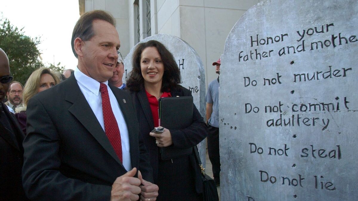 FILE- This Nov. 12, 2003 file photo shows Roy Moore looking at a Ten Commandments display as he arrives at the Judicial Building in Montgomery, Ala. Roy Moore wouldn't stand a chance in many U.S. Senate races after defying federal court orders, describing Islam as a false religion, calling homosexuality evil and pulling out a revolver on stage before hundreds of supporters. Moore is the GOP candidate for senate. He will face Democratic nominee Doug Jones. (AP Photo/Dave Martin, File)