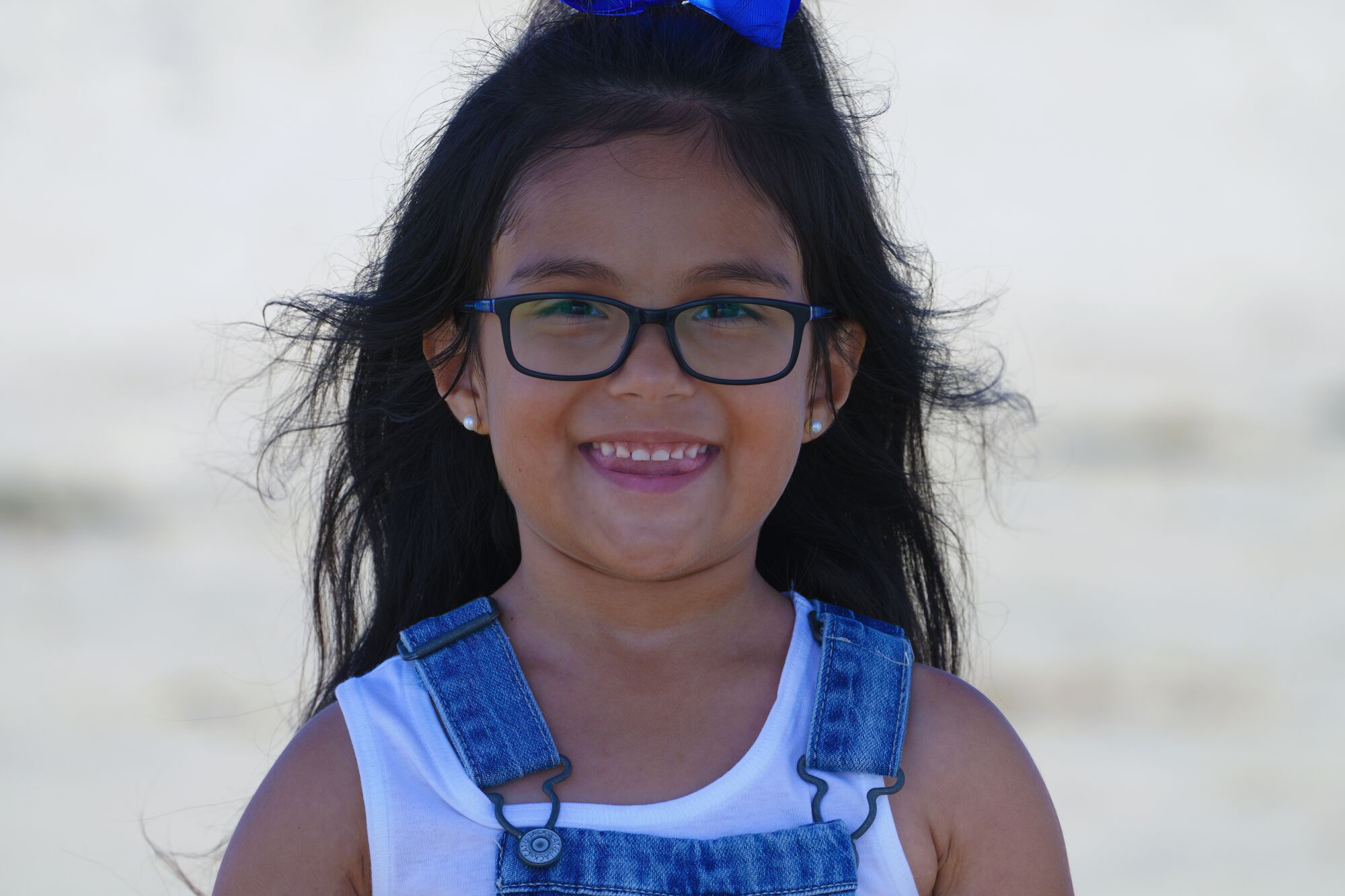 una niña sonríe de pie en la playa