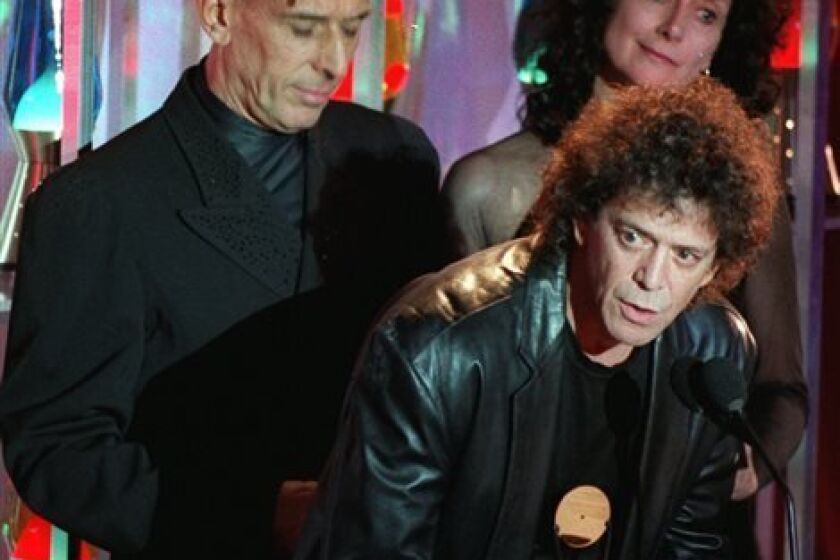 FILE - In this Jan. 17, 1996 file photo, Lou Reed takes the podium as the Velvet Underground, the group he once headed, is inducted into the Rock and Roll Hall of Fame during a ceremony in New York s Waldorf-Astoria Hotel. Band mate John Cale is at left, and at right is Martha Morrison, accepting for late band member Sterling Morrison. Punk-poet, rock legend Lou Reed is dead of a liver-related ailment, his literary agen said Sunday, Oct. 27, 2013. He was 71. (AP Photo/Mark Lennihan, File)