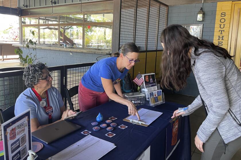 FILE - Volunteer signature gatherers Judy Robbins, left, and Lara Cerri, center, collect Grace Harders' signature on a petition to enshrine the right to abortion in Arizona's consitution, April 10, 2024, in Phoenix. Abortion rights advocates are set to deliver about 800,000 petition signatures Wednesday, July 3, 2024, in hopes of getting abortion rights on the November general election ballot. (AP Photo/Anita Snow, File)