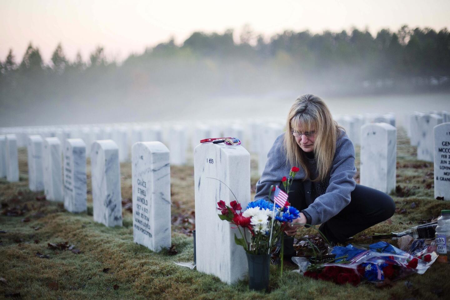 Jiffy Helton Sarver places flowers at the grave of her son, 1st Lt. Joseph Helton, Jr., who was killed while serving in Iraq in 2009, at Georgia National Cemetery. "This was his favorite time of day," said Sarver. "He loved sunrises."