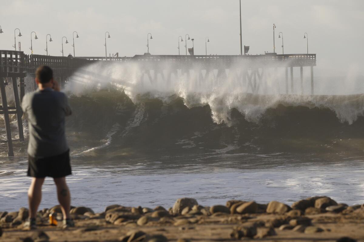 David Volk of San Francisco watches as the Ventura Pier is pounded by heavy surf on Jan. 7. The area is expected to see more big waves this week.