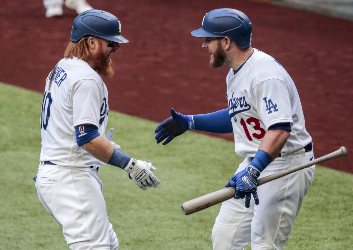 Dodgers third baseman Justin Turner, left, is greeted by Max Muncy after hitting a solo home run.