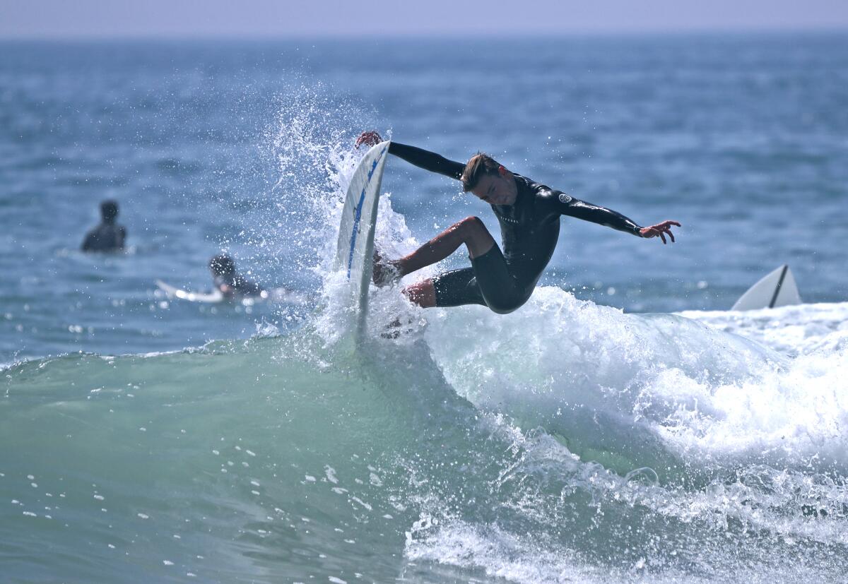 A surfer grabs a nice wave near the pier in Huntington Beach on Friday. 