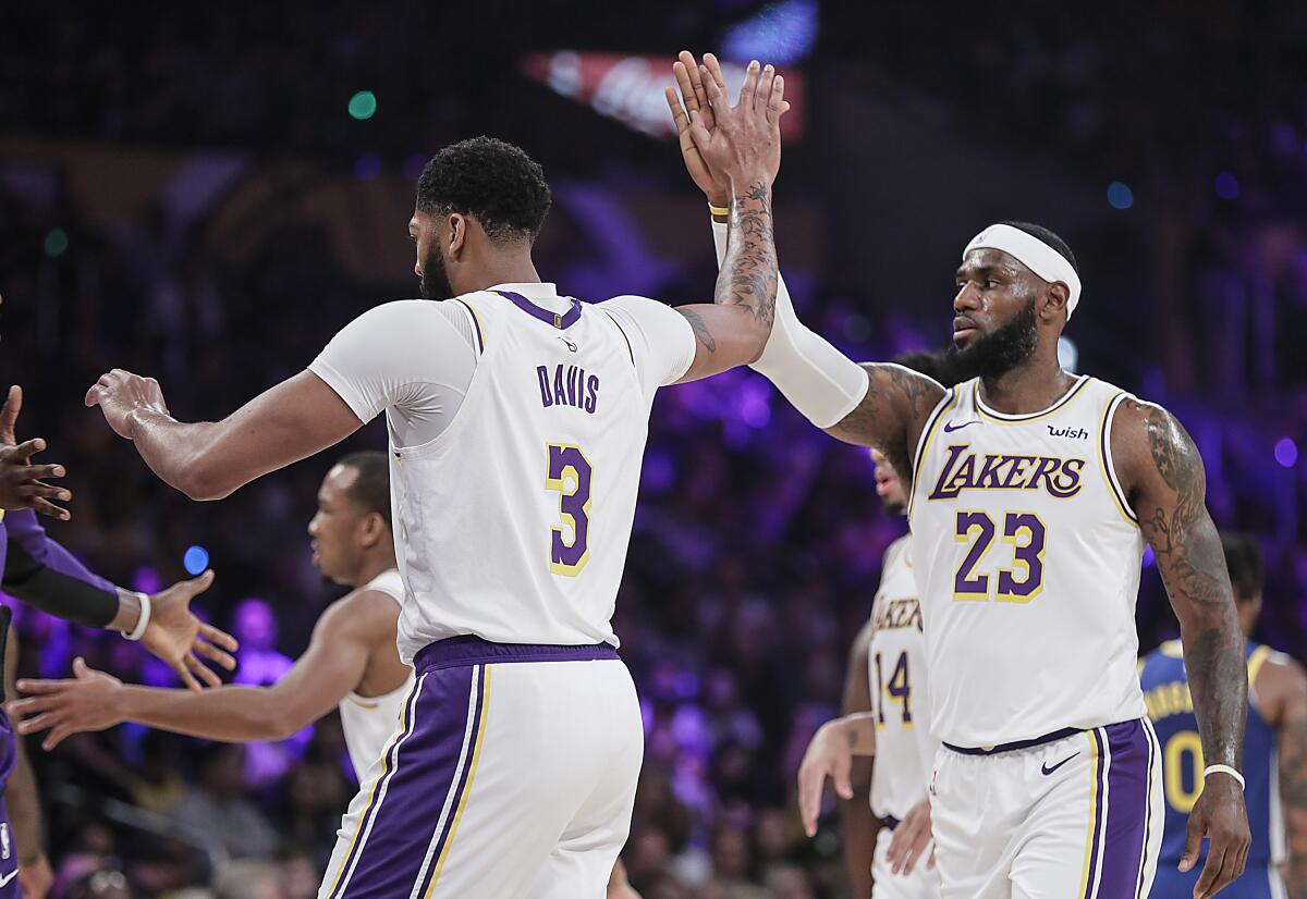 Lakers forwards Anthony Davis (3) and LeBron James (23) celebrate after a play during a preseason game against the Warriors.