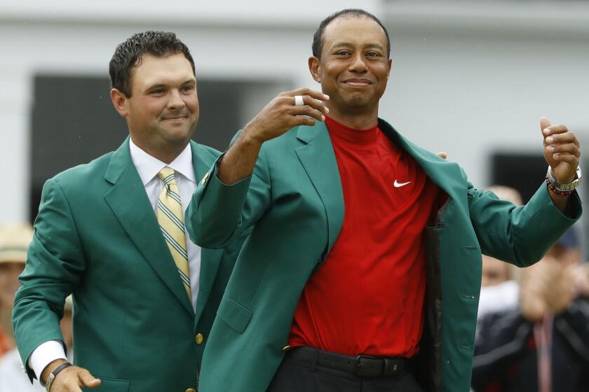 Patrick Reed helps Tiger Woods with his green jacket after Woods won the Masters golf tournament Sunday, April 14, 2019, in Augusta, Ga. (AP Photo/Matt Slocum)