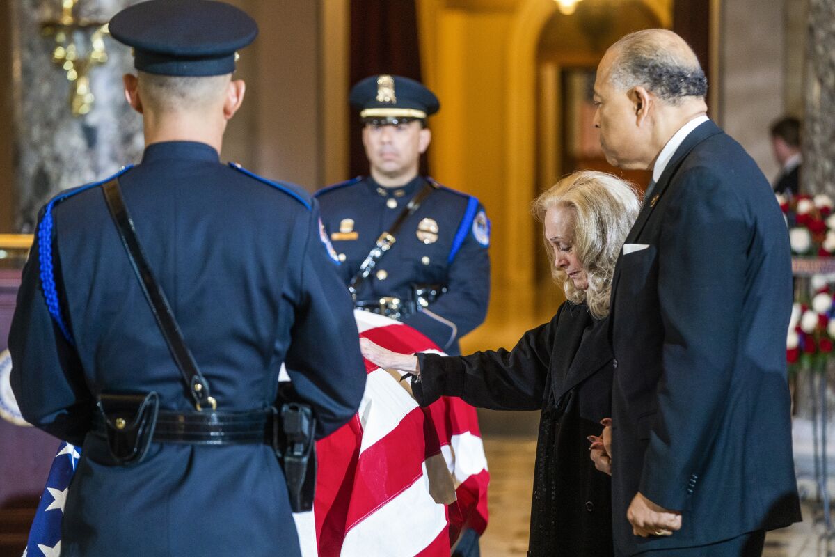 Anne Walton touches the flag-draped casket of her husband, former Rep. Don Young, in the Capitol