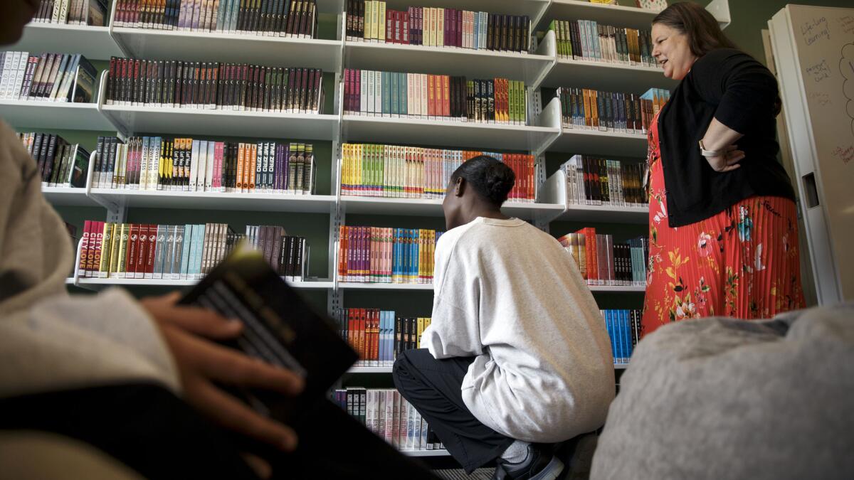 Amy Trulock, right, a full-time on-site librarian, watches as the girls browse the shelves inside the Los Padrinos Juvenile Hall library.