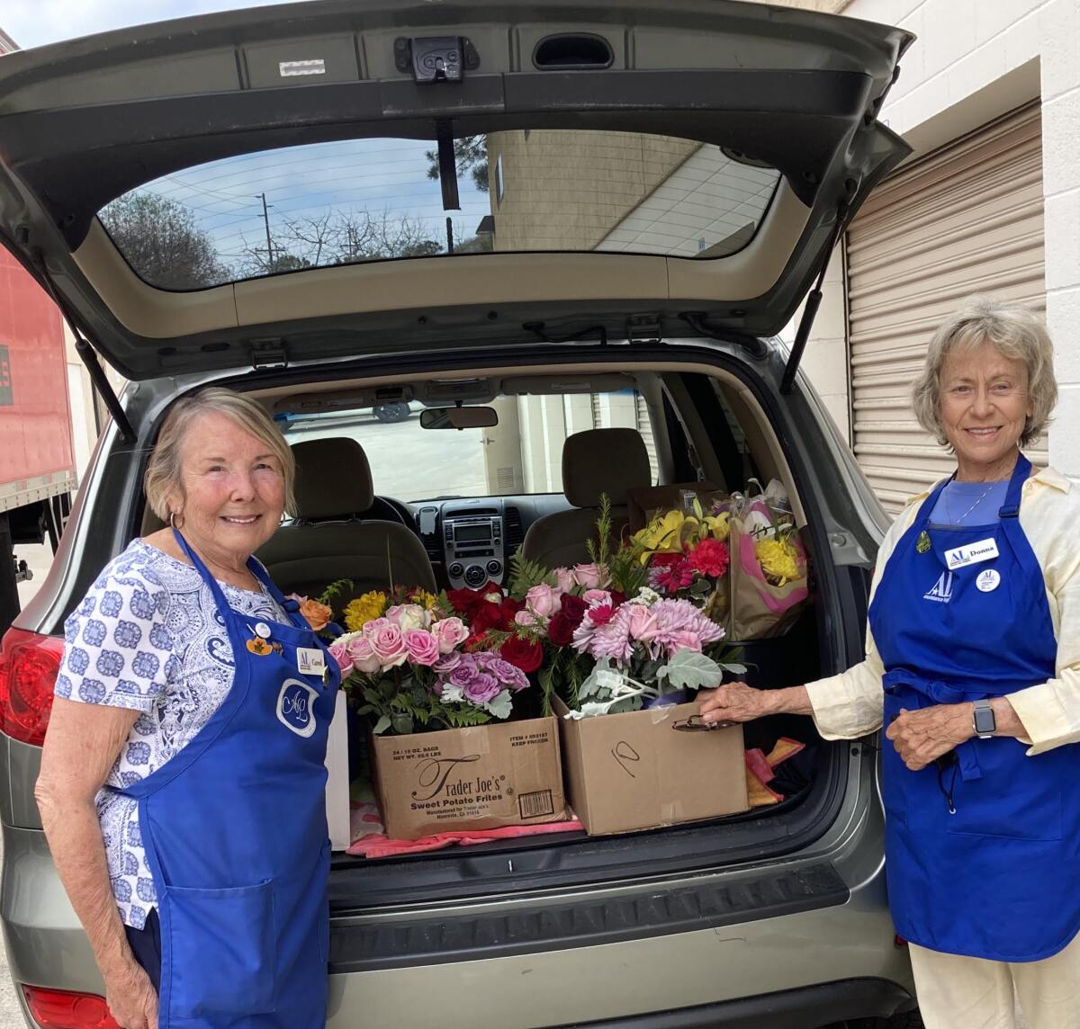 Carol Tuggey and Donna Buys load bouquets for delivery