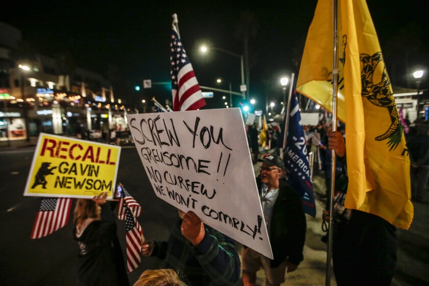 Protesters carry "Screw you Greusome"[sic] and "Recall Gavin Newsom" signs at a Huntington Beach protest.
