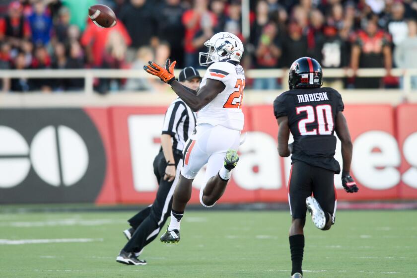 Oklahoma State receiver James Washington makes a catch in front of Texas Tech's Tevin Madison during the fourth quarter of a game on Oct. 31.