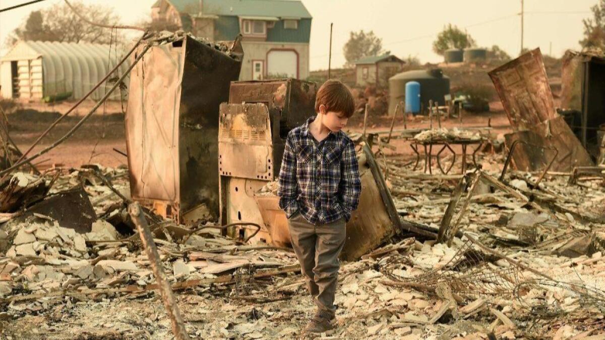 Jacob Saylors, 11, walks through the burned remains of his home in Paradise, Calif.