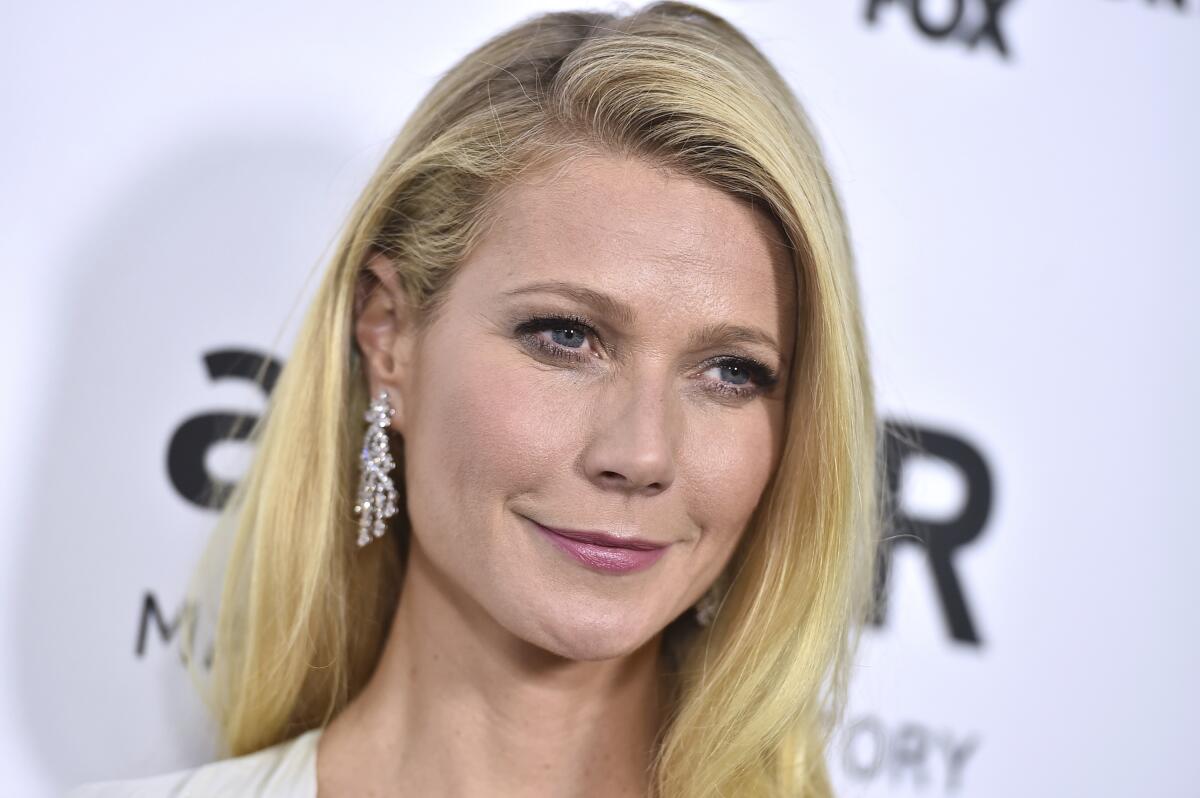 Gwyneth Paltrow with her blond hair parted on the side and wearing dangly diamond earrings. 