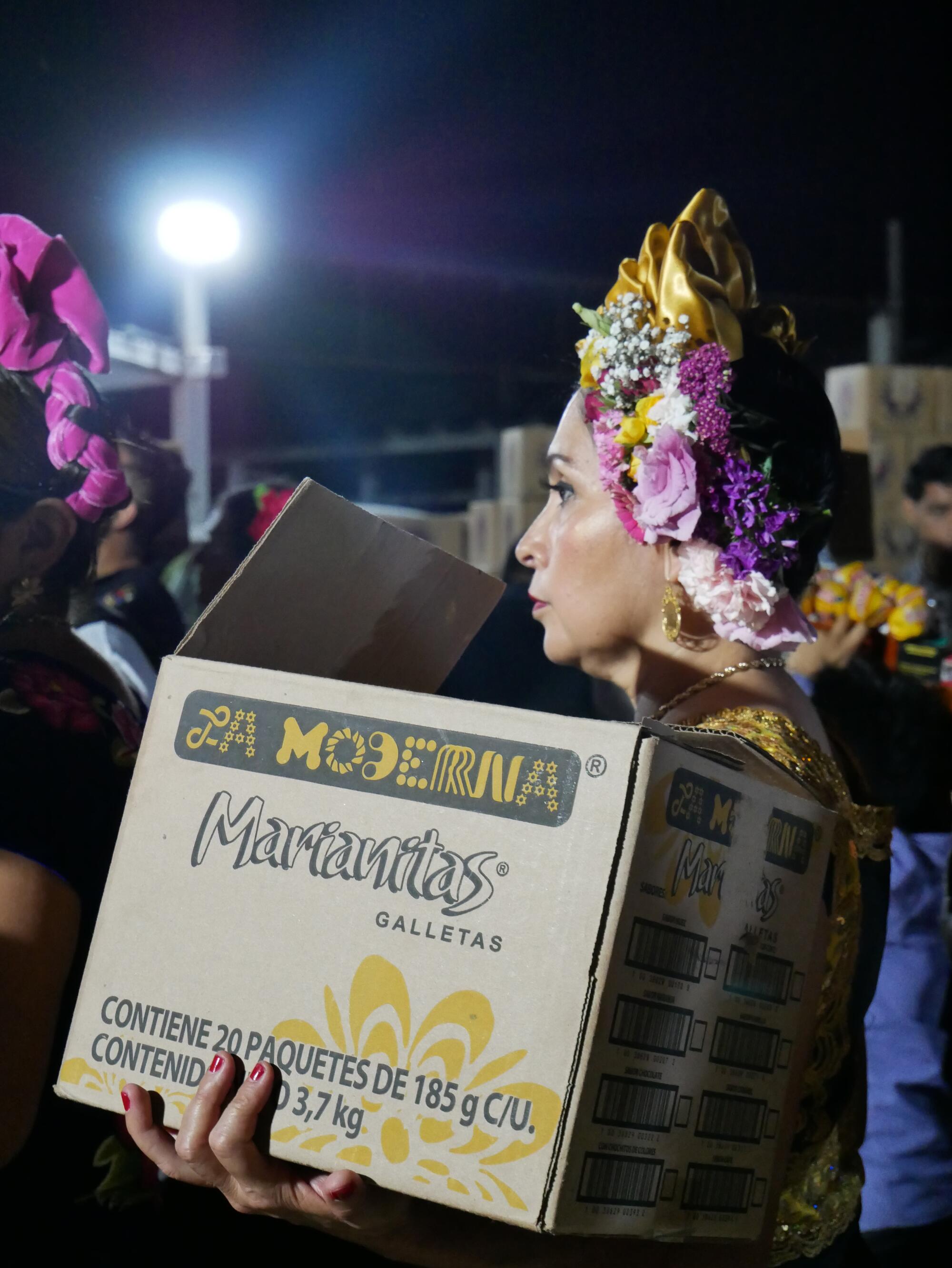 An attendee at the Vela wears an intricate headpiece while carrying food into the all-night event.