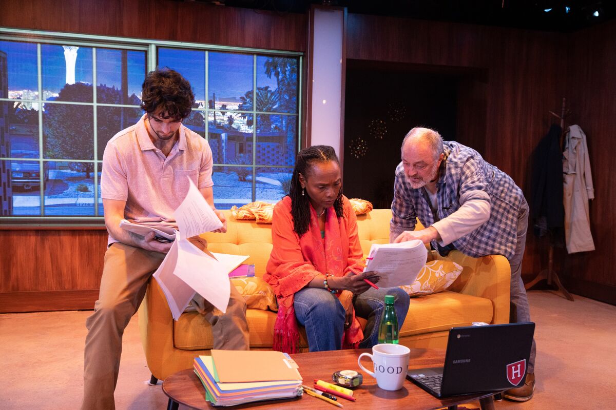 Three people huddle over the pages of a manuscript.