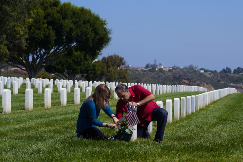 Fort Rosecrans National Cemetery, CA - August 09: At Fort Rosecrans National Cemetery, CA., on Monday, Aug. 9, 2021., Kenny , Nicochea Sr, and Lori Nicochea place an arrangement of red and white roses their son’s Kenny Nicochea, Jr., headstone. Kenny Nicochea, Jr. was killed in explosion while serving in the U.S. Army in Afghanistan on December 12th, 2010. (Nelvin C. Cepeda / The San Diego Union-Tribune)