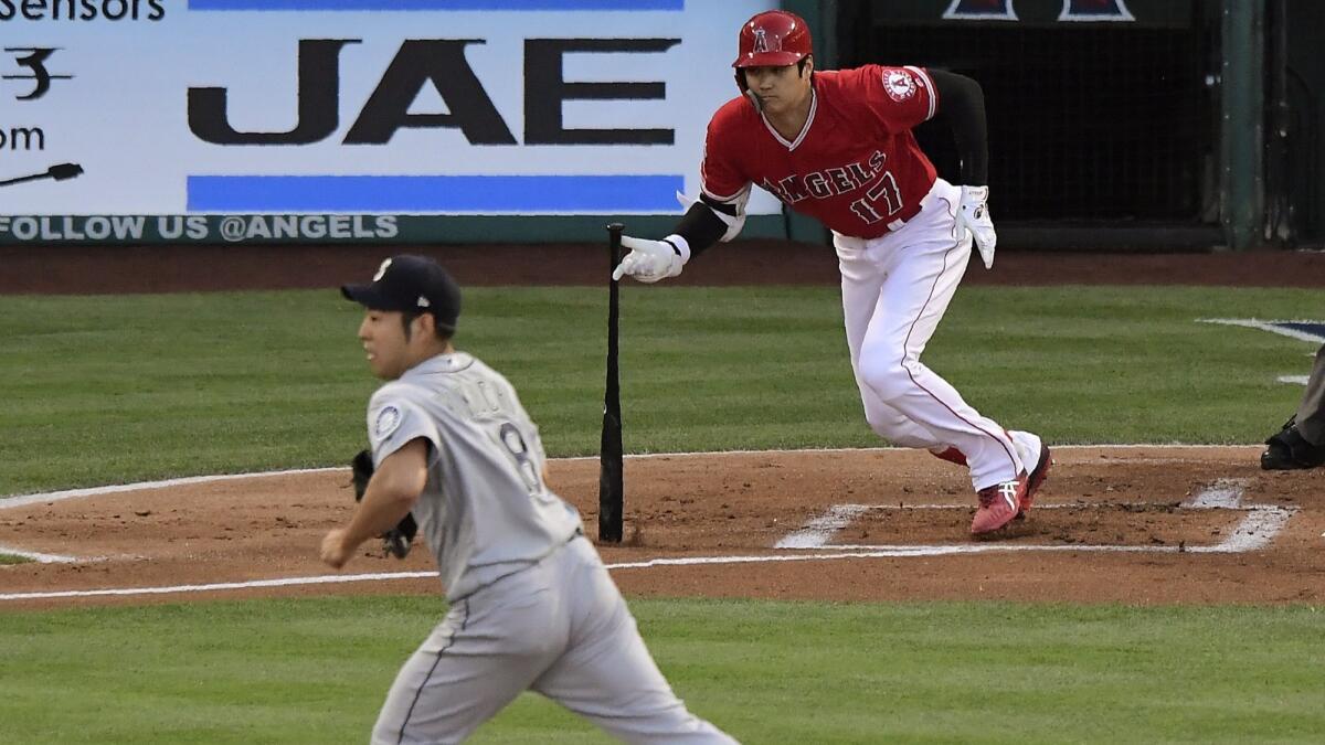 Angels designated hitter Shohei Ohtani hits a single as Seattle Mariners starting pitcher Yusei Kikuchi runs to back up the first baseman during the first inning on Saturday.