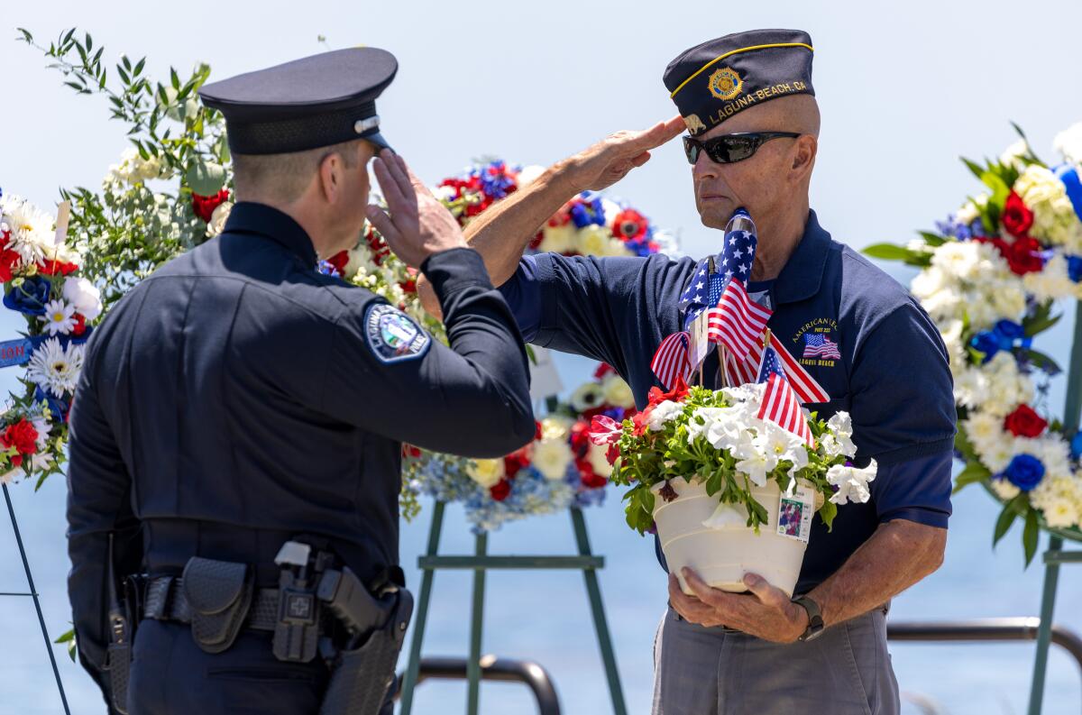 A Laguna Beach police officer hands flowers to memorialize men and women who died in military service.