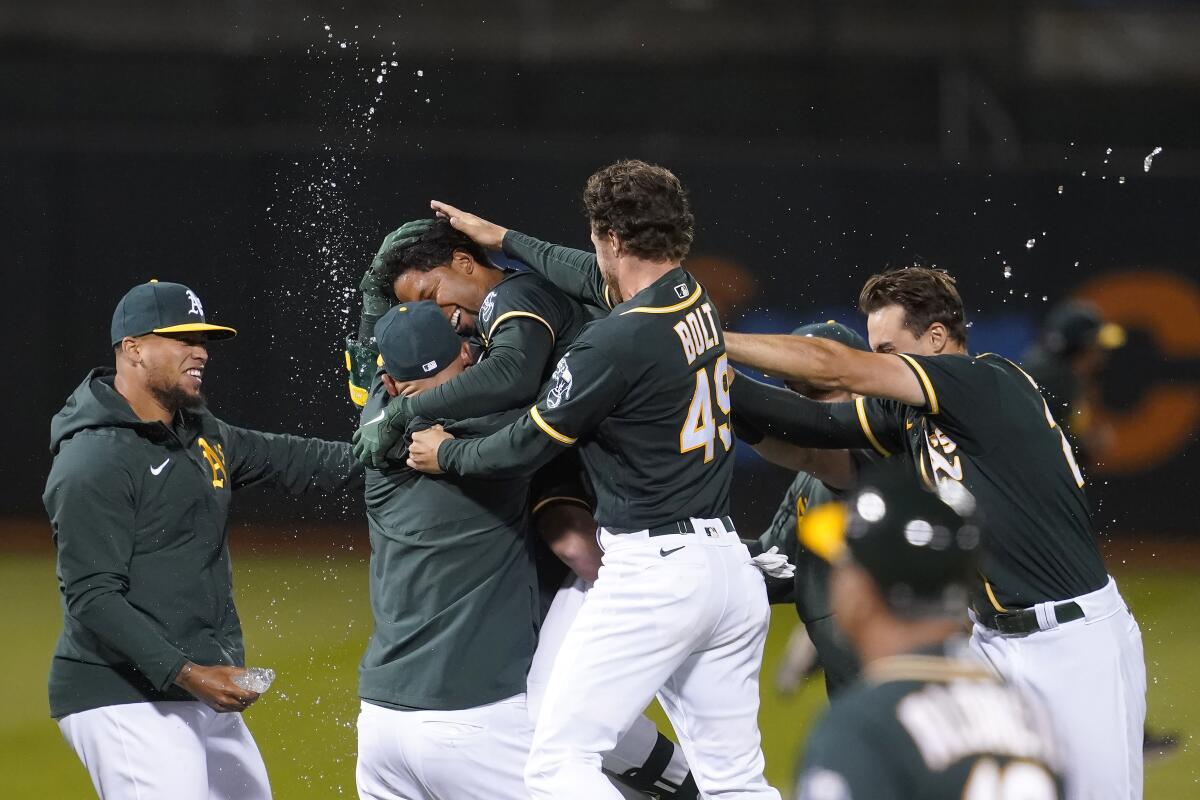 Oakland Athletics' Elvis Andrus, third from left, is congratulated by teammates after hitting a single to score Matt Chapman during the ninth inning of a baseball game against the Kansas City Royals in Oakland, Calif., Friday, June 11, 2021. (AP Photo/Jeff Chiu)