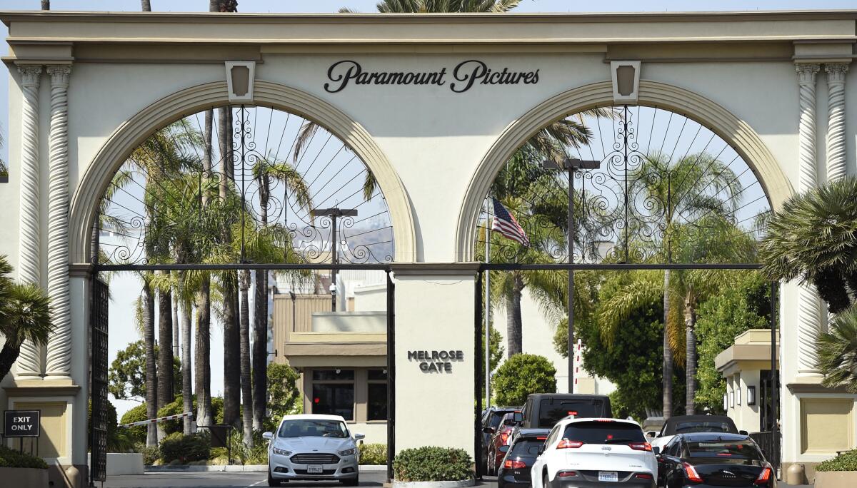 Cars enter and leave from a film studio's arched gates.