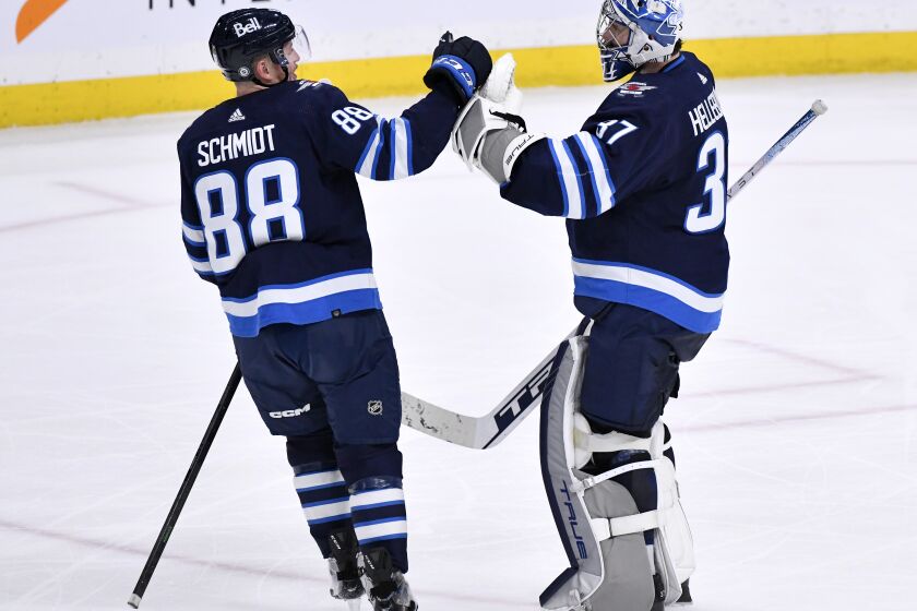 Winnipeg Jets goaltender Connor Hellebuyck (37) celebrates the win over the Arizona Coyotes with Nate Schmidt (88) during the third period of an NHL hockey game, Tuesday, March 21, 2023 in Winnipeg, Manitoba. (Fred Greenslade/The Canadian Press via AP)