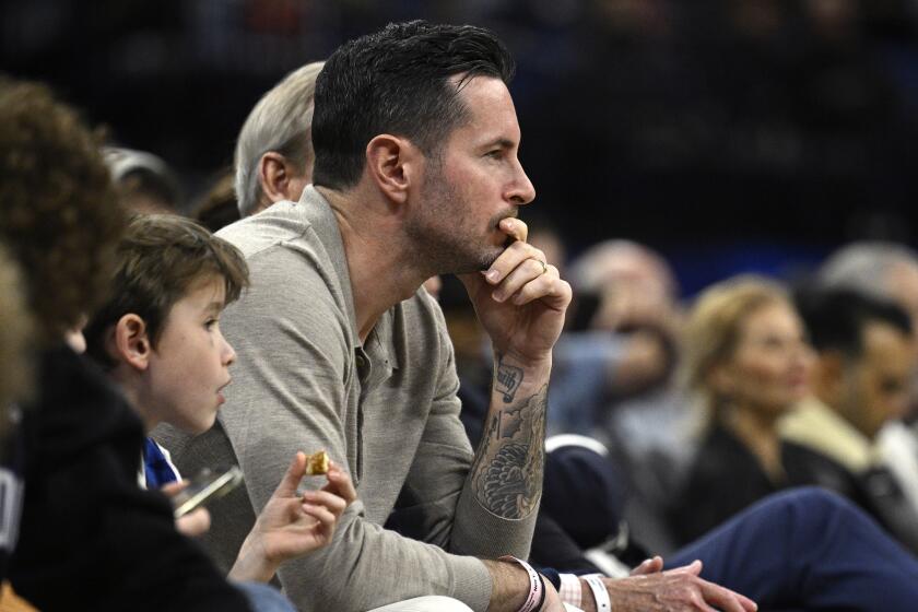 Former Orlando Magic guard JJ Redick, center, watches from a court side seat during the first half.