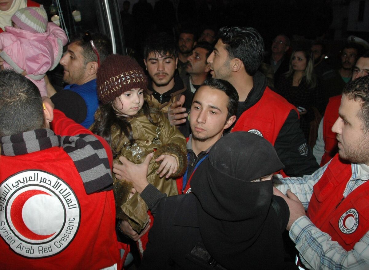 Syrian Arab Red Crescent staff help civilians exit a bus after they were evacuated from rebel-controlled, army-besieged districts of Homs, Syria.