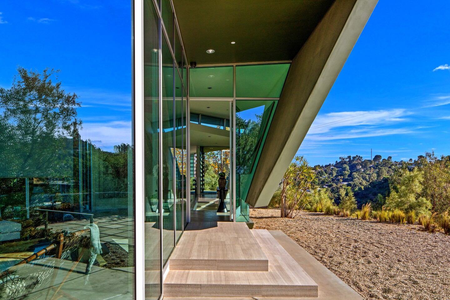 The dramatic Hollywood Hills home of musician Pharrell was designed by Hagy Belzberg and completed in 2007. Set atop a ridge, the modern showplace features an open-concept floor plan, walls of glass and a minimalist-vibe kitchen. A suspended chrome fireplace commands attention in the living room, which is bordered on all sides by floor-to-ceiling windows.